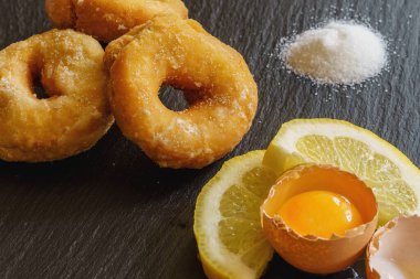 Şekerin, limonun ve yumurta sarısının dokusunu yeni yapılmış çöreklerin yanında gösteren yüksek açılı bir yakın çekim..