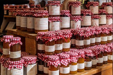 Barselona, İspanya - 24 Ocak 2026: Ahşap bir standın üzerinde geleneksel kırmızı kareli kumaş kaplamaları bulunan ev yapımı marmelat kavanozları.