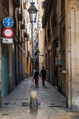 Bir erkek ve kadın, Avrupa 'da tarihi dar bir sokakta yürürken el ele tutuşuyorlar..