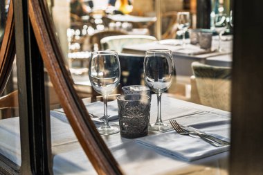 Restoranda beyaz bir masa örtüsüne yerleştirilmiş temiz cam eşyalar ve çatal bıçaklar üzerine seçici bir odak noktası..