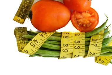 Taze domates ve yeşil fasulye sarı bir mezura ile sarılmış..