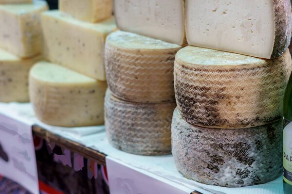 Assorted wheels of cheese on display at a market.