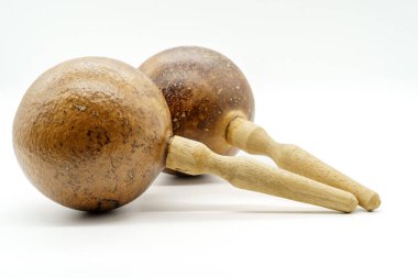 Yuvarlak sukabakları ve beyaz arka planda oyulmuş sapları olan bir çift tahta marakas.