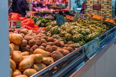 Barselona, İspanya - 3 Şubat 2026: Pazar tezgahındaki patatesler ve enginarlar da dahil olmak üzere taze mevsimlik sebzelere yakından bakmak, sağlıklı beslenme ve vejetaryen diyet kavramları için mükemmel.