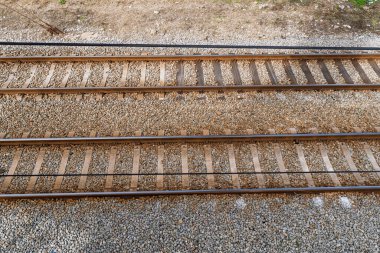 Çelik raylı paralel demiryolu raylarının ve çakıl balast üzerindeki ahşap pusucuların, dış nakliye altyapısı arka planının genel manzarası..