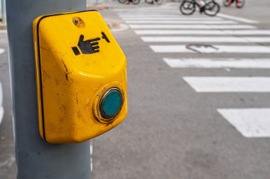 Bulanık zebra yaya geçidi ve arka planda bisikletçiler olan sarı yaya geçidi düğmesine yakın plan, şehir sokak güvenliği kavramı, sığ alan derinliği.