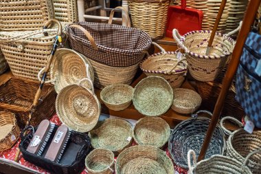 Bir market tezgahında satılık sepet ve tepsilerin renkli çeşitleri, kırsal el yapımı depolama ve ev dekorasyonu öğeleri birbirine yakın bir şekilde gösteriliyor.