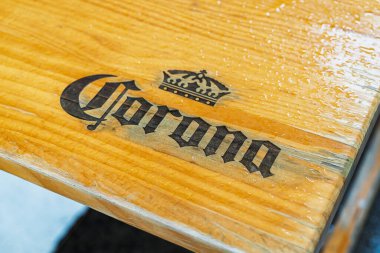 Barselona, İspanya - 7 Şubat 2026: Islak ahşap masa yüzeyine basılmış Corona Extra marka logosu, içecek endüstrisi için ideal.