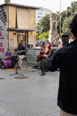 Barcelona, İspanya - 14 Şubat 2026: Pembe saçlı bir kadın gitarist ve bir davulcu Arc de Triomf yakınlarında canlı müzik icra ediyor.