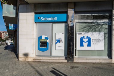 Barselona, İspanya - 22 Şubat 2026: Banco Sabadell 'in bir banka şubesinin dış görünüşü ATM ve sigorta reklam afişleri, finans haberleri, bankacılık sektörü güncellemeleri ve ekonomik makaleler için mükemmel.