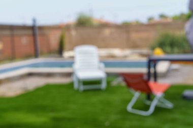 Blurred and abstract image of a garden with hammocks and grass. Blurred image to use as background.