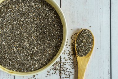Chia tohumları ve tahta kaşıkla kase. Kırsal ahşap masa.