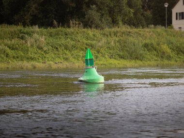 Almanya 'da bir nehirde yeşil şamandıra. İşaret, tekne sürücülerinin nehri nerede geçeceğini gösteriyor. Güvenlik nedeniyle seyrüsefer ekipmanları.
