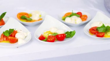 Küçük bir tabakta fesleğen aperatifli domates ve mozarella. Bir restoranda yemek servisi. Zengin misafirler için nefis taze İtalyan yemekleri. Klasik Akdeniz gastronomisi..