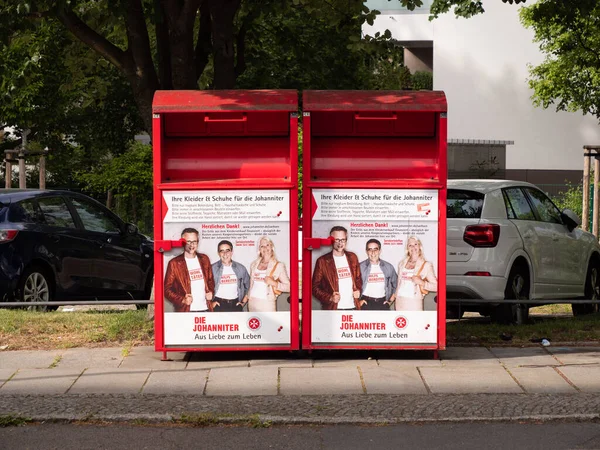 DRESDEN, ALMANY - 29. Mayıs 2022: Eski giysi konteynırları kullanılmış giysileri toplamak için. Hristiyan yardım örgütü Die Johanniter kırmızı kutuları bir caddenin yanına koydu..