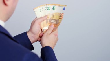 İş adamı para yığınından hayran topluyor. Takım elbiseli zengin bir gencin elinde bir sürü Euro banknotları var. Omuz hizasından..