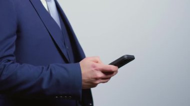 Takım elbiseli bir adam cep telefonu kullanıyor. İş adamı mobil bir uygulamayı dinliyor. Bir danışman işi için iletişim hizmetlerini kullanıyor..