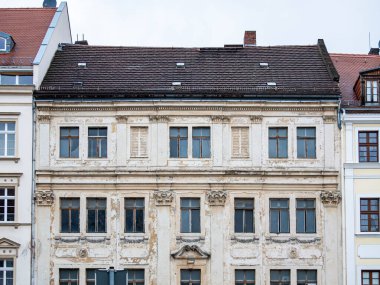 Şehir caddesinde eski bir bina. Yıpranmış dış yüzeyi olan boş ev diğer binaların arasında yer alıyor. Ön cephesi parlak ve boyası dökülüyor. Yenileme çok pahalı..