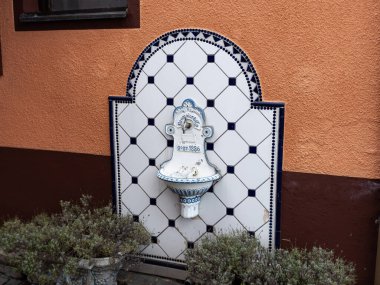 İSVEÇ, ALMANA - 31. Ağustos 2023: Neumaier Co tarafından kurulan antik duvar çeşmesi (1886). Antik açık hava lavabosu bir binanın dış tarafına monte edilmiş. Bu tür musluklar Bavyera 'da bulunabilir.