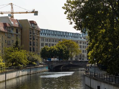 BERLİN, ALMANY - 26. Mayıs 2023: Mitte ilçesinde Spreekanal ve Gruenstrassenbruecke. Şehir merkezinde mimarlık ve büyük ağaçlar. Kanalın yanında gezinti güvertesi olan sokak manzarası.