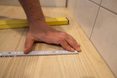 Mutfak için bir atölyenin uzunluğunu ölçmek. Bir daireyi yenileyip yeni mobilyalar yapmak. Bir marangoz ev ortamında marangozluk yapıyor..