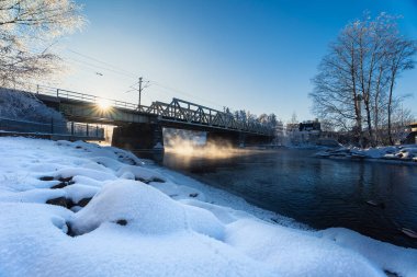 Buz gibi kıyı şeridi ve soğuk kış koşullarında nehir üzerindeki köprü yapısı.