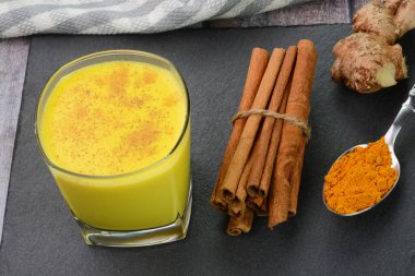 Zerdeçal sütü, tarçın tozuyla süslenmiş cam bir bardaktaki altın süt olarak da adlandırılır.