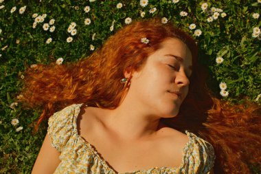 Kırmızı kıvırcık saçlı güzel kız bahar mevsiminde açık havada