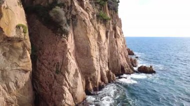 Güçlü okyanus dalgaları rüzgarlı havada engebeli kıyı şeridi boyunca kayalara ve kayalıklara çarpıyor..