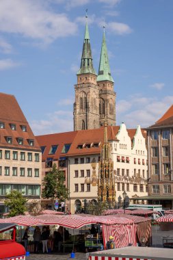 Almanya 'nın Nuremberg şehrinde Hauptmarkt' ta Schner Brunnen çeşmesi ve St. Sebald Kilisesi 'nin ikiz kuleleri yer alıyor..