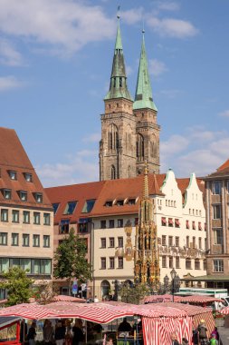 Almanya 'nın Nuremberg şehrinde Hauptmarkt' ta Schner Brunnen çeşmesi ve St. Sebald Kilisesi 'nin ikiz kuleleri yer alıyor..