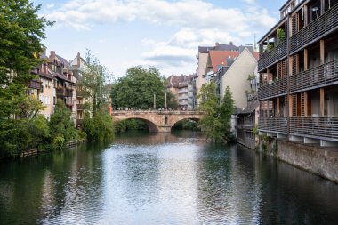 Karlsbrcke 'nin Nuremberg, Bavyera, Almanya' daki manzarası, tarihi taş mimarisi, nehir üzerindeki yansımaları ve günbatımında büyüleyici eski kasaba atmosferini içeriyor..