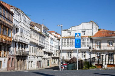 İspanya 'nın Betanzos kentindeki Mandeo Nehri üzerindeki Ponte Vella köprüsünden görülen geleneksel Galiçya beyaz binaları yemyeşil yemyeşil.