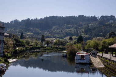 İspanya 'nın Betanzos kentindeki Mandeo Nehri üzerindeki Ponte Vella köprüsünün manzarası yemyeşil ve tarihi mimariyle çevrili..