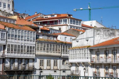 İspanya 'nın Betanzos kentindeki Mandeo Nehri üzerindeki Ponte Vella köprüsünden görülen geleneksel Galiçya beyaz binaları yemyeşil yemyeşil.