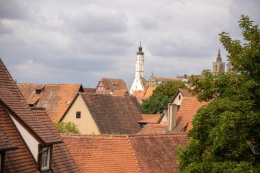Almanya 'nın Bavyera kentindeki ortaçağ şehir duvarından Rothenburg ob der Tauber' in panoramik manzarasına göre tarihi çatılar, kuleler ve manzaralı güçlendirilmiş mimari.