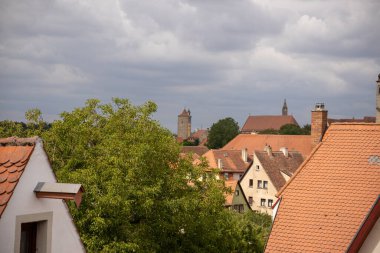 Almanya 'nın Bavyera kentindeki ortaçağ şehir duvarından Rothenburg ob der Tauber' in panoramik manzarasına göre tarihi çatılar, kuleler ve manzaralı güçlendirilmiş mimari.