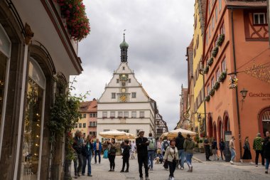Rothenburg ob der Tauber, Almanya Pazar Meydanı, tarihi belediye binası kulesi, Ratstrinkstube Saat Kulesi, yarım kereste evler, kaldırım taşı sokaklar, Bavyera kentinde çeşme ve dükkanlar.