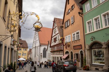 Rothenburg ob der Tauber, Almanya Pazar Meydanı, tarihi belediye binası kulesi, Ratstrinkstube Saat Kulesi, yarım kereste evler, kaldırım taşı sokaklar, Bavyera kentinde çeşme ve dükkanlar.