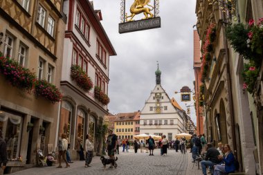 Rothenburg ob der Tauber, Almanya Pazar Meydanı, tarihi belediye binası kulesi, Ratstrinkstube Saat Kulesi, yarım kereste evler, kaldırım taşı sokaklar, Bavyera kentinde çeşme ve dükkanlar.