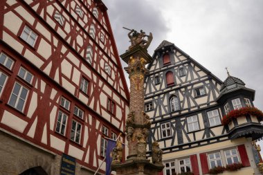 Rothenburg ob der Tauber, Almanya Pazar Meydanı, tarihi belediye binası kulesi, Ratstrinkstube Saat Kulesi, yarım kereste evler, kaldırım taşı sokaklar, Bavyera kentinde çeşme ve dükkanlar.