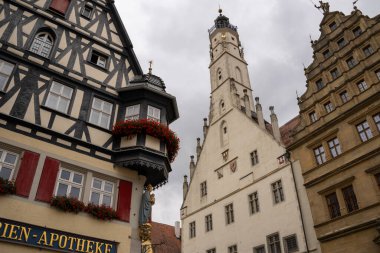 Rothenburg ob der Tauber, Almanya Pazar Meydanı, tarihi belediye binası kulesi, Ratstrinkstube Saat Kulesi, yarım kereste evler, kaldırım taşı sokaklar, Bavyera kentinde çeşme ve dükkanlar.