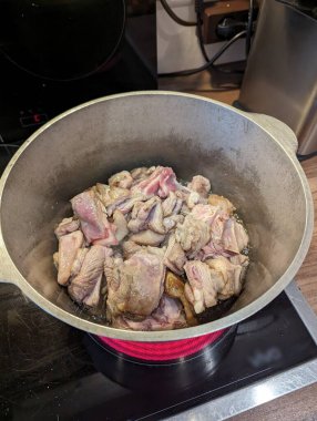 Pforzheim, Almanya Dezember çiğ tavuk parçaları elektrikli ocakta kaynıyor, kasaplar ve soluk derili kanatlar kesiliyor.