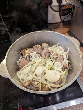 Pforzheim, Almanya Dezember ağır tencerede çiğ soğan halkaları ile eti dilimledi, sıvılar serbest bırakıldı ve kenarları kahverengileşti, hazırlayıcı sote