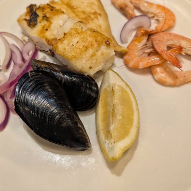 Bir kepçe çikolata ve vanilyalı dondurma, çilekli kırmızı meyve jölesi, bir dilim muz ve küçük parça pasta ve tatlı tabağında haşlanmış armut..