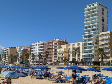 Llored de Mar İspanya 15 Eylül 2024 Şemsiyeli ve Şemsiyeli Kalabalık Plajı. Mavi Şemsiyeler ve Güneş Banyoları Altın Kumu Çok Katlı Sahil Binaları ve Ailelerin Önünde Doldurun