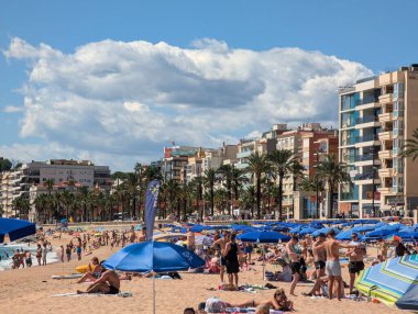 Llored de Mar İspanya 15 Eylül 2024 Mavi Şemsiyeli ve güneşli sahil şeridi, Aile, Tedarikçi, Çocuklar Suyun Yanında Oynuyor, Palmline