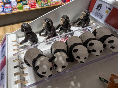 Pforzheim Almanya 25 Şubat 2026 Panda ve Maymun figürleri sergilendi, Plush Panda Oyuncakları ve Küçük Metal Heykeller Flüoresan Işıklar Altındaki Perakende Tezgahında Düzenlendi,