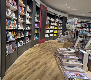 Pforzheim Almanya 25 Şubat 2026 Sıcak ahşap zemin ve süpürücü raflarla dolu kıvrımlı kitapçı koridoru, Geniş ışıklandırma ve yuvarlak tasarım, sakin atmosfer