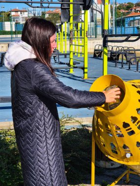 Plastiği geri dönüşüm için parlak renkli, delikli çöp tenekesi kullanan birinin kenar görüntüsü. 